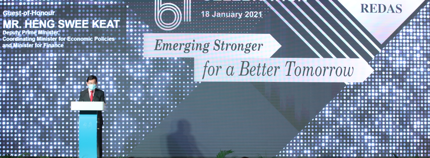 Man at podium, wearing mask, backdrop says "Emerging Stronger for a Better Tomorrow."